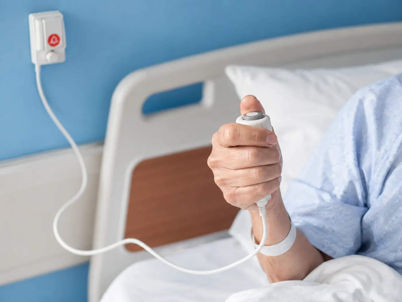 Patient using a nurse call pendant from a hospital bed